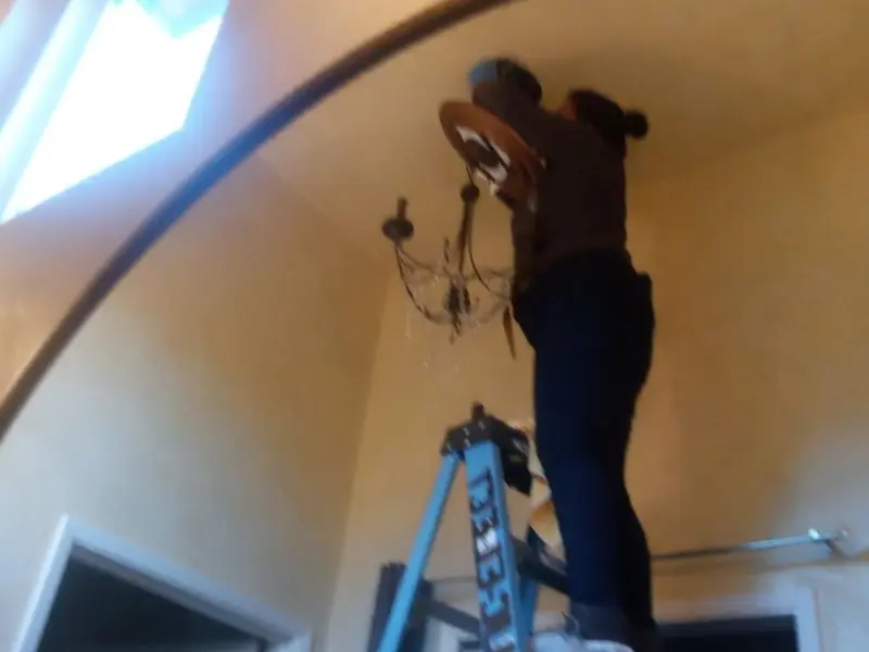 Electrician installing a chandelier in a Hellam residence